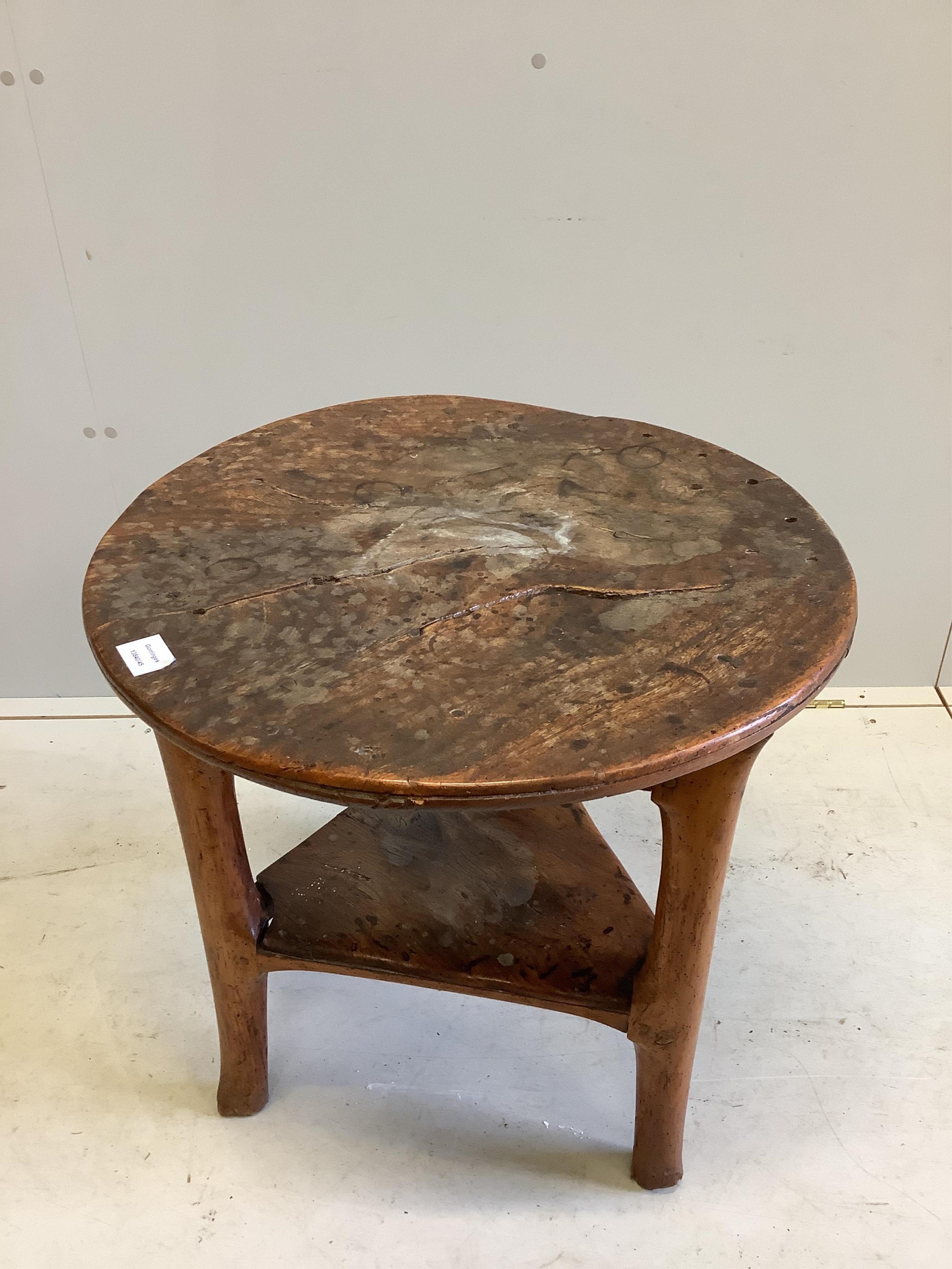 An 18th century elm cricket table, width 63cm, height 64cm. Condition - extensive splitting and old patches and repairs to the top, legs probably reduced, but full of character